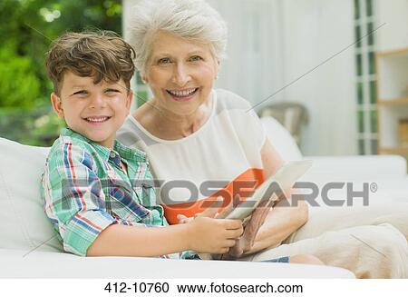 Stock Image - Older woman and grandson using digital tablet. Fotosearch