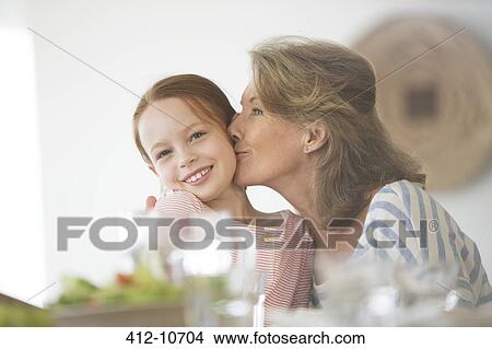 Older woman kissing granddaughter at table View Large Photo Image Picture - Older woman kissing granddaughter at table. Fotosearch