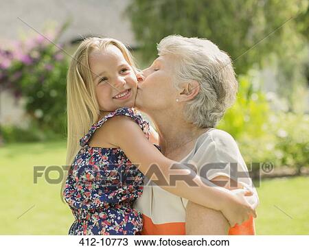 Stock Image - Older woman kissing granddaughter outdoors. Fotosearch