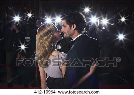 Picture - Paparazzi photographing celebrity couple kissing at red carpet event. Fotosearch