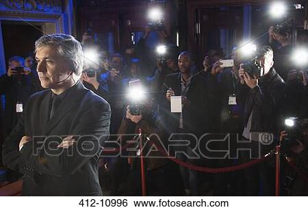 Paparazzi using flash photography behind bodyguard at red carpet event View Large Photo Image Stock Photograph - Paparazzi using flash photography behind bodyguard at red carpet event. Fotosearch