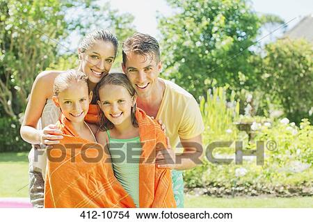 Picture - Parents wrapping daughters in towels in backyard. Fotosearch
