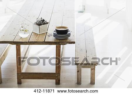 Stock Image - Plates and silverware stacked on wooden table. Fotosearch