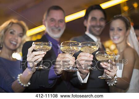 Stock Photo - Portrait of bride and groom toasting champagne with parents. Fotosearch