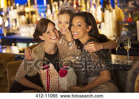 Stock Photography - Portrait of enthusiastic women holding gifts and hugging in luxury bar. Fotosearch