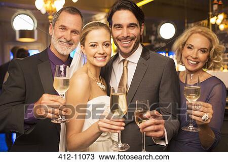 Portrait of happy bride and groom toasting champagne flutes with parents View Large Photo Image Stock Image - Portrait of happy bride and groom toasting champagne flutes with parents. Fotosearch
