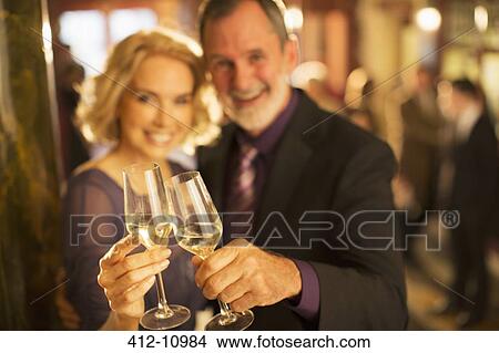 Portrait of well dressed couple toasting champagne glasses in theater lobby View Large Photo Image Picture - Portrait of well dressed couple toasting champagne glasses in theater lobby. Fotosearch