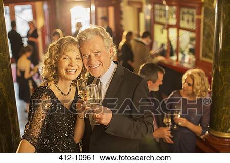 Stock Image - Portrait of well dressed couple toasting champagne flutes. Fotosearch