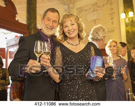 Portrait of well dressed couple toasting champagne flutes in theater lobby View Large Photo Image Stock Photograph - Portrait of well dressed couple toasting champagne flutes in theater lobby. Fotosearch