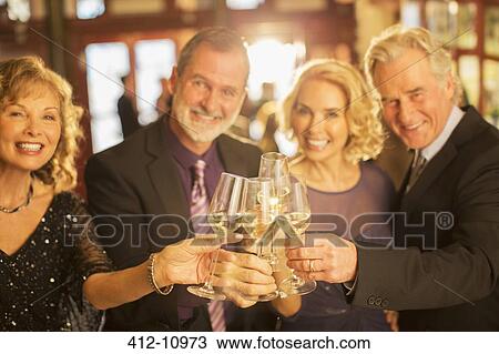 Portrait of well dressed couples toasting champagne flutes in theater lobby View Large Photo Image Stock Image - Portrait of well dressed couples toasting champagne flutes in theater lobby. Fotosearch