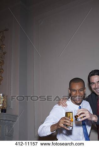 Stock Photo - Portrait of well dressed men toasting beer and cocktail. Fotosearch