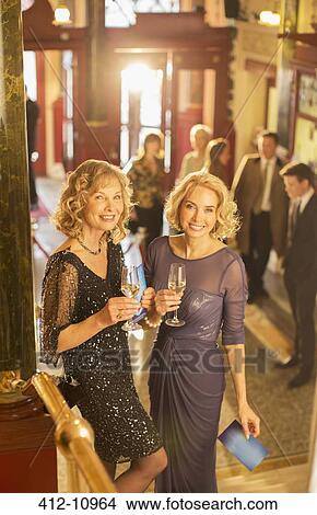 Portrait of well dressed women drinking champagne in theater lobby View Large Photo Image Picture - Portrait of well dressed women drinking champagne in theater lobby. Fotosearch