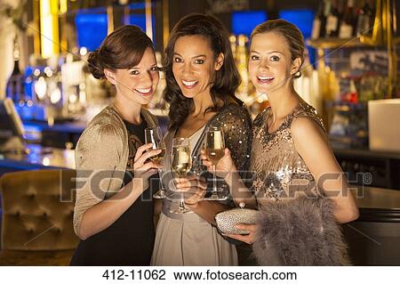 Portrait of well dressed women smiling with champagne flutes in luxury nightclub View Large Photo Image Stock Image - Portrait of well dressed women smiling with champagne flutes in luxury nightclub. Fotosearch