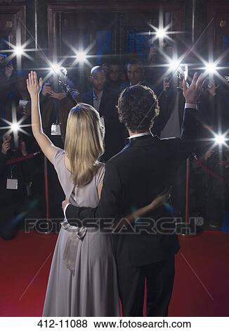 Rear view of well dressed celebrity couple waving to paparazzi on red carpet View Large Photo Image Stock Photo - Rear view of well dressed celebrity couple waving to paparazzi on red carpet. Fotosearch