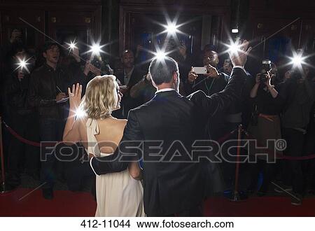 Rear view of well dressed couple waving to paparazzi at red carpet event View Large Photo Image Picture - Rear view of well dressed couple waving to paparazzi at red carpet event. Fotosearch