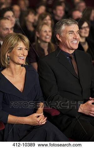 Smiling couple in theater audience View Large Photo Image Stock Photo - Smiling couple in theater audience. Fotosearch