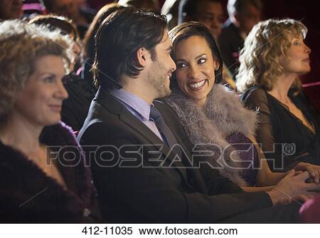 Stock Photography - Smiling couple talking in theater audience. Fotosearch