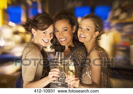 Stock Image - Smiling women toasting champagne glasses in nightclub. Fotosearch