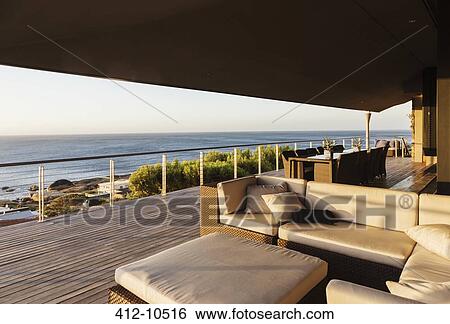 Stock Photograph - Sofa and table on luxury patio overlooking ocean. Fotosearch