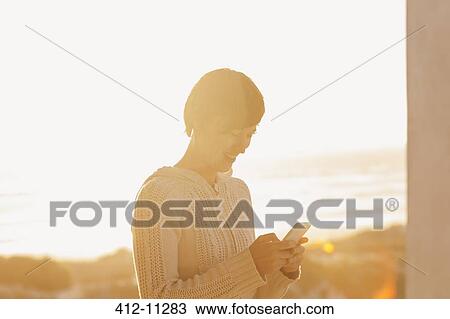 Sun shining behind woman using cell phone View Large Photo Image Stock Image - Sun shining behind woman using cell phone. Fotosearch