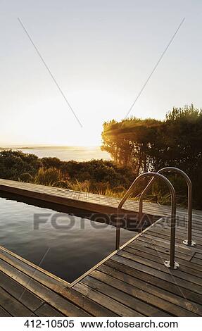 Stock Photography - Sunset in background of lap pool. Fotosearch