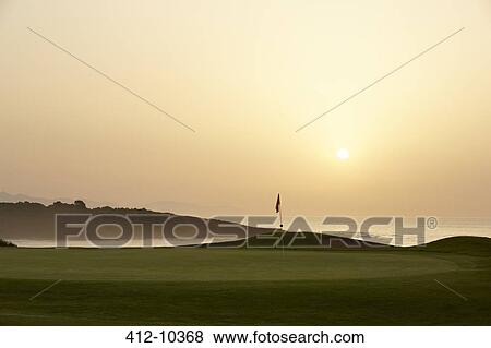 Stock Photo - Sunset over ocean and golf course. Fotosearch