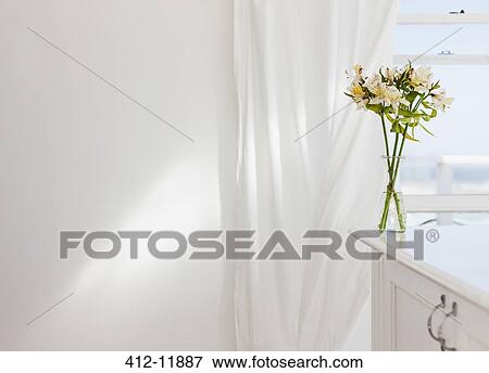 Vase of flowers on desk in white room View Large Photo Image Stock Photo - Vase of flowers on desk in white room. Fotosearch