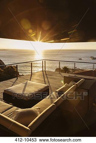 Stock Image - View of sunset over ocean from luxury balcony. Fotosearch