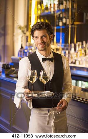 Well dressed bartender carrying wine glasses on tray in luxury bar View Large Photo Image Stock Photo - Well dressed bartender carrying wine glasses on tray in luxury bar. Fotosearch