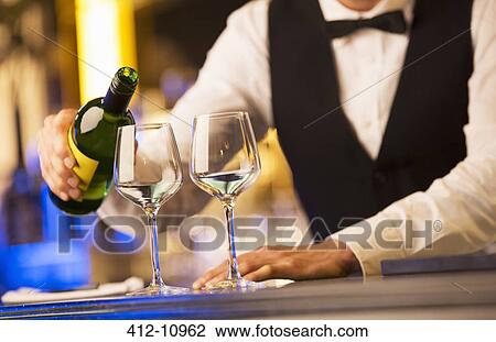 Stock Image - Well dressed bartender pouring wine. Fotosearch