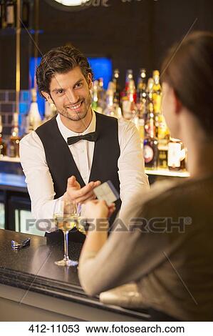 Well dressed bartender taking credit card from customer in luxury bar View Large Photo Image Stock Image - Well dressed bartender taking credit card from customer in luxury bar. Fotosearch