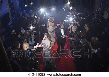 Stock Image - Well dressed celebrities signing autographs on red carpet. Fotosearch