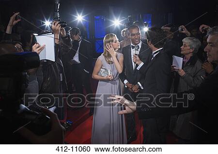 Stock Image - Well dressed celebrity couple being interviewed on red carpet. Fotosearch