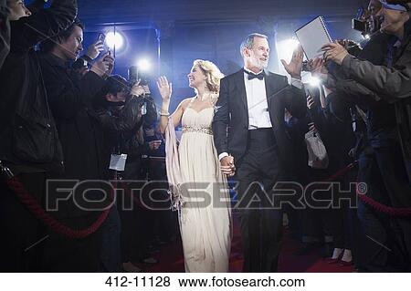 Well dressed celebrity couple walking through paparazzi on red carpet View Large Photo Image Stock Photo - Well dressed celebrity couple walking through paparazzi on red carpet. Fotosearch