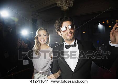 Well dressed celebrity couple waving to paparazzi on red carpet View Large Photo Image Stock Image - Well dressed celebrity couple waving to paparazzi on red carpet. Fotosearch