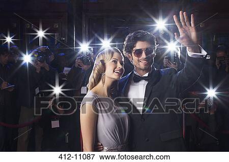 Well dressed celebrity couple waving to paparazzi at red carpet event View Large Photo Image Stock Photo - Well dressed celebrity couple waving to paparazzi at red carpet event. Fotosearch