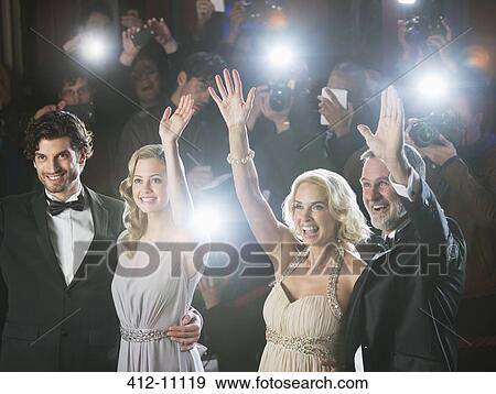 Stock Photo - Well dressed celebrity couples waving to paparazzi at red carpet event. Fotosearch