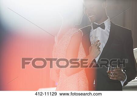 Stock Photo - Well dressed couple drinking champagne and cocktail. Fotosearch