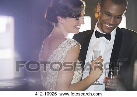 Stock Photograph - Well dressed couple drinking champagne and cocktail. Fotosearch