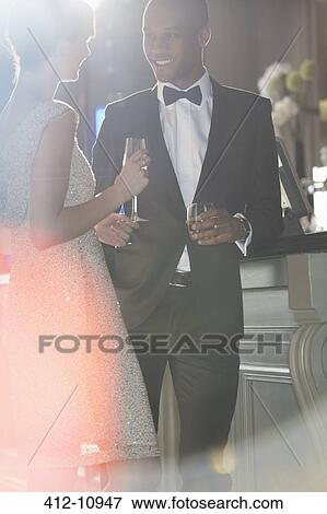 Well dressed couple talking and drinking champagne and cocktail View Large Photo Image Stock Photo - Well dressed couple talking and drinking champagne and cocktail. Fotosearch