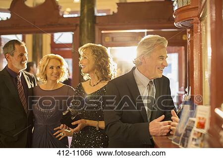 Well dressed couples at counter in theater lobby View Large Photo Image Stock Photograph - Well dressed couples at counter in theater lobby. Fotosearch