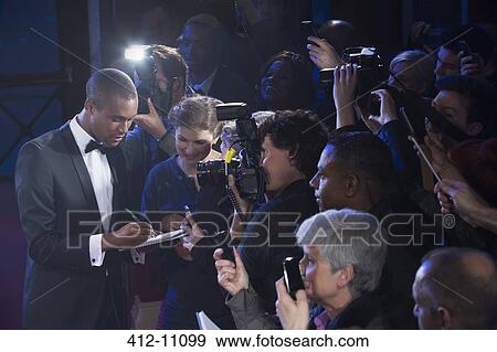 Stock Photo - Well dressed male celebrity signing autographs at red carpet event. Fotosearch