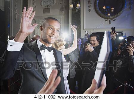 Well dressed male celebrity waving to fans and paparazzi at red carpet event View Large Photo Image Stock Image - Well dressed male celebrity waving to fans and paparazzi at red carpet event. Fotosearch
