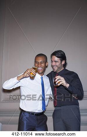 Picture - Well dressed men hugging and drinking beer and cocktail. Fotosearch