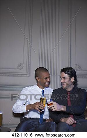Stock Photograph - Well dressed men toasting beer and cocktails. Fotosearch