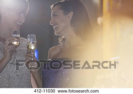 Stock Image - Well dressed women drinking champagne in luxury bar. Fotosearch