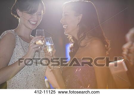 Stock Photography - Well dressed women toasting champagne flutes. Fotosearch