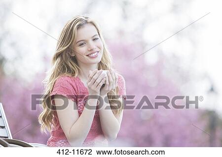 Stock Image - Woman enjoying cup of coffee in park. Fotosearch
