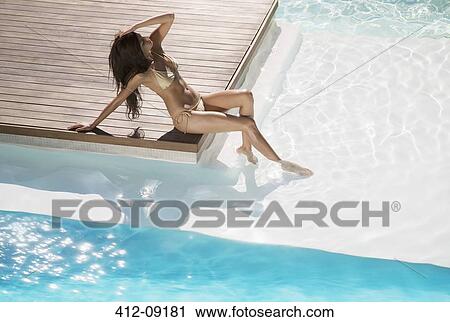 Stock Image - Woman relaxing at swimming pool. Fotosearch