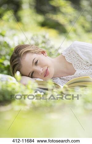 Woman relaxing in grass with book View Large Photo Image Picture - Woman relaxing in grass with book. Fotosearch